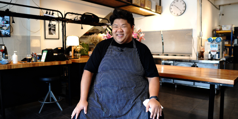 Ahong in an apron smiling sitting in Grub by Ahong & Friends