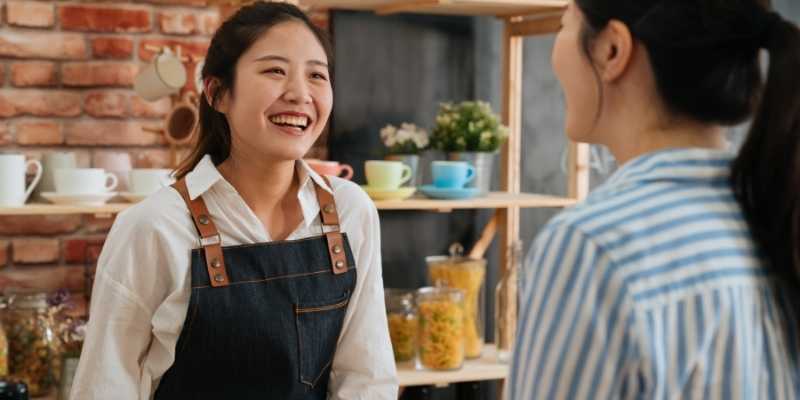 Asian business owner smiling and chatting with customer at cafe or restaurant