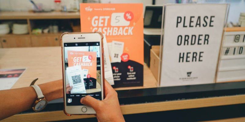 A person scanning a receipt to redeem cashback at a restaurant on the phone.