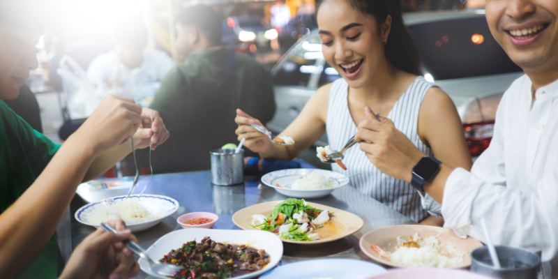 A group of happy customers smiling while eating at a restaurant.