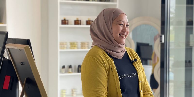 Datin Eidza, owner of 5Luxe Scents Co., sitting down while smiling