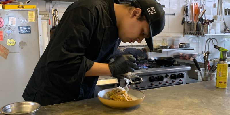 A Back Alley Pasta Bar staff shredding cheese on a pasta
